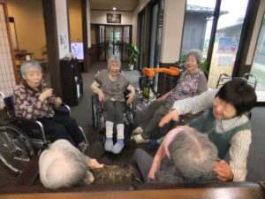 居室階の廊下でレクリエーション活動を行う複数の高齢入居者たち